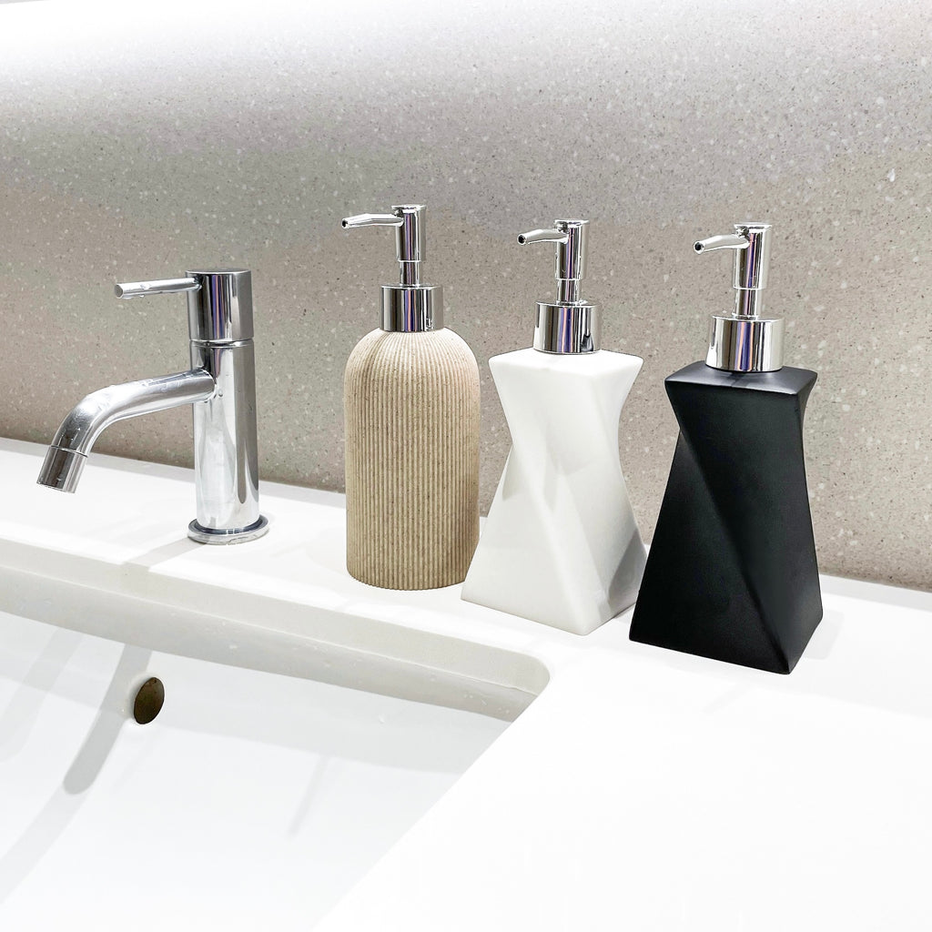 Three soap dispensers on the side of the bathroom sink.